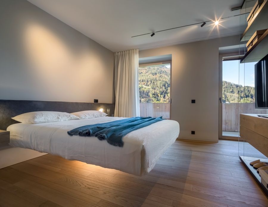 Camera da letto di Casa LAGO Dolomiti con vetrata affacciata sulla valle del Primiero
