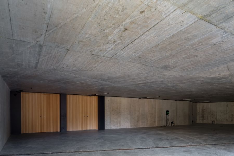 Lo spazio interrato di Casa LAGO Dolomiti con soffitto in cemento a vista e ante in legno